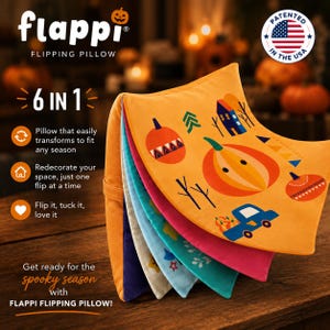 May include: A Flappi Flipping Pillow with a 6-in-1 design. The top layer is orange with a graphic print of pumpkins, a house, and a blue truck. Beneath it are layers in pink, teal, light blue, cream, and purple. Text includes Flappi Flipping Pillow.