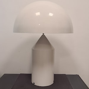 May include: White table lamp with a large, round, dome-shaped shade and a cylindrical base.