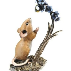 May include: A small, brown mouse figurine with a long tail, standing on its hind legs and reaching up to a blue flower with a bee on it. The figurine is made of resin and has a detailed finish.