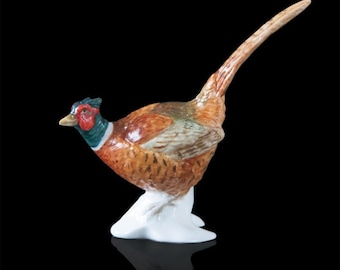May include: A porcelain figurine of a pheasant with brown, red, and green feathers. The pheasant is standing on a white base.