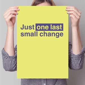 May include: A person holds up a yellow poster with the text "Just one last small change" in purple letters.