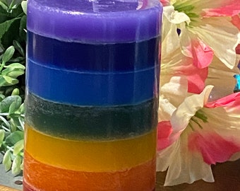 Könnte beinhalten: Eine mehrfarbige Kerze mit Schichten aus lila, blau, grün, gelb, orange und rotem Wachs. Die Kerze ist zylindrisch und hat einen weißen Docht.