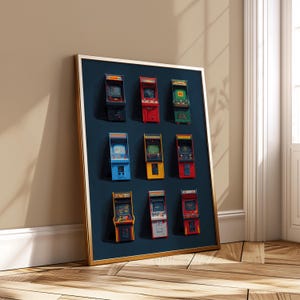 Puede incluir: Un cuadro enmarcado con nueve máquinas recreativas en miniatura de varios colores, incluyendo rojo, azul y amarillo. Las máquinas recreativas están dispuestas sobre un fondo azul oscuro dentro de un marco dorado. El cuadro está apoyado contra una pared.