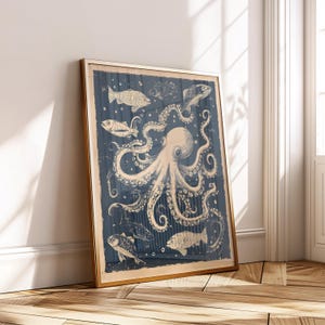 May include: Framed art print with a vintage illustration of an octopus and fish in a deep blue sea. The octopus and fish are cream-coloured, set against a textured background. The frame is gold-coloured.