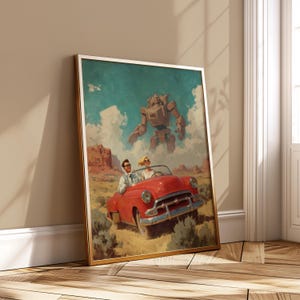 May include: A framed print shows a red convertible with two people driving through a desert landscape, with a large robot in the sky. The artwork has a retro, mid-century modern style and is presented in a gold frame, reminiscent of vintage posters.