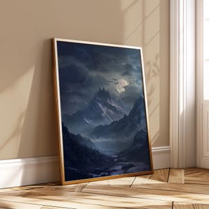 May include: A framed art print of a fantasy landscape. The image shows a mountain range under a dark, cloudy sky with a full moon. A castle sits atop a mountain, and a river flows through the valley. The frame is gold.