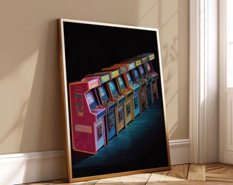 May include: A framed print featuring a row of vintage arcade game machines. The machines are in various colors, including pink, orange, blue, and yellow, with illuminated screens and colorful accents. The print has a gold frame and is leaning against a wall.