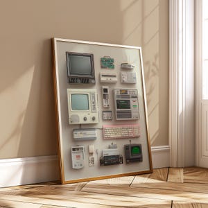 May include: A framed print featuring a collection of vintage electronics, including televisions, a circuit board, a keyboard, and a remote control. The items are arranged on a light gray background within a gold frame, leaning against a beige wall.
