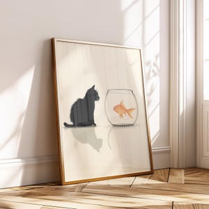 May include: Framed art print featuring a black cat gazing at a goldfish in a glass bowl. The cat is depicted in a seated position, with its shadow visible. The goldfish is orange, and the background is a neutral beige.