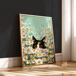 Può includere: Stampa artistica incorniciata con un gatto che sbuca da un campo di margherite. Il gatto ha macchie nere, bianche e arancioni con grandi occhi gialli. Le margherite hanno petali bianchi e centri gialli, su uno sfondo verde chiaro.