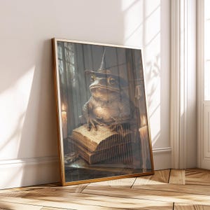 May include: A framed art print depicting a toad in a wizard's hat, sitting on old books. The artwork has a vintage style, with warm lighting and a gold frame. Candles are placed on either side of the toad, enhancing the magical theme. The frame is gold.