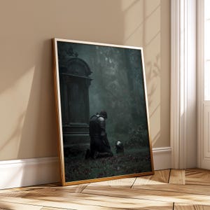 May include: A framed print depicting a figure in medieval armour kneeling in a forest, with a helmet on the ground. A weathered tombstone is in the background. The print has a gold frame, creating a gothic atmosphere. The scene is dark and atmospheric.