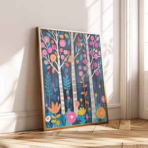 Op de afbeelding: Een ingelijste kunstdruk met een gestileerde bosscène. Witte berken met kleurrijke bloemen en bladeren in tinten roze, oranje en blauw staan tegen een donkerblauwe achtergrond. Het kunstwerk wordt gepresenteerd in een gouden lijst.