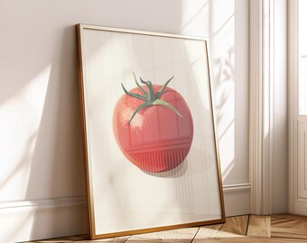 Op de afbeelding: Een ingelijste kunstdruk met een gestileerde illustratie van een rijpe rode tomaat met groene bladeren. Het kunstwerk heeft een gouden lijst en leunt tegen een witte muur en houten vloer, wat een moderne uitstraling creëert.