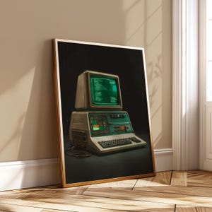 May include: A framed print of a retro computer with a green screen showing code. The computer has a keyboard and a separate monitor. The print is in a gold frame and leans against a wall.