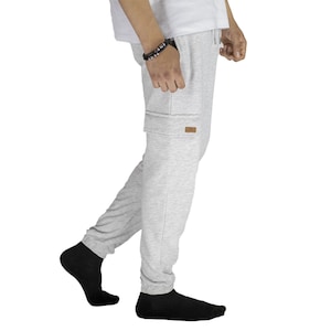May include: Gray sweatpants with a cargo pocket on the left leg. The sweatpants have a drawstring waistband and a relaxed fit.