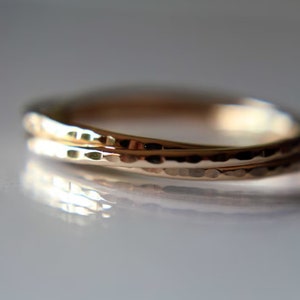 May include: Two gold rings, one slightly larger than the other, are intertwined. Both rings have a hammered texture.