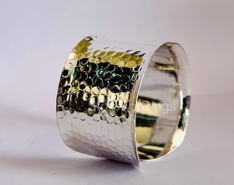 May include: A silver hammered cuff bracelet with a textured surface.