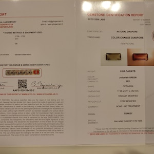 May include: A gemstone identification report for a 6.85 carat, yellowish-green to red color change diaspore. The report details the gemstone's weight, color, shape, dimensions, and origin. The report is from GFCO Gemological Laboratory, a trademark of Geafinco SA, Switzerland.