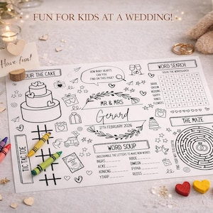 Puede incluir: Un mantel individual de actividades de boda con una tarta, una búsqueda de palabras y un laberinto. Incluye crayones, lápices y decoraciones en forma de corazón. El texto dice "Fun for Kids at a Wedding!" y "Mr & Mrs Gerard 27th February 2026."