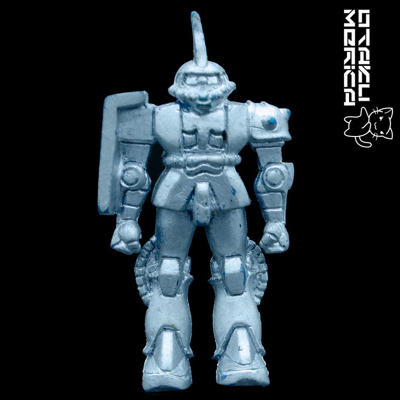 K&ouml;nnte beinhalten: Eine hellblaue Spielzeug-Roboterfigur mit einem Schild und einer hohen antennenartigen Struktur auf dem Kopf. Der Roboter hat detaillierte Panzerplatten und steht vor einem schwarzen Hintergrund. Das Bild enth&auml;lt auch wei&szlig;en Text und eine Katzenillustration.