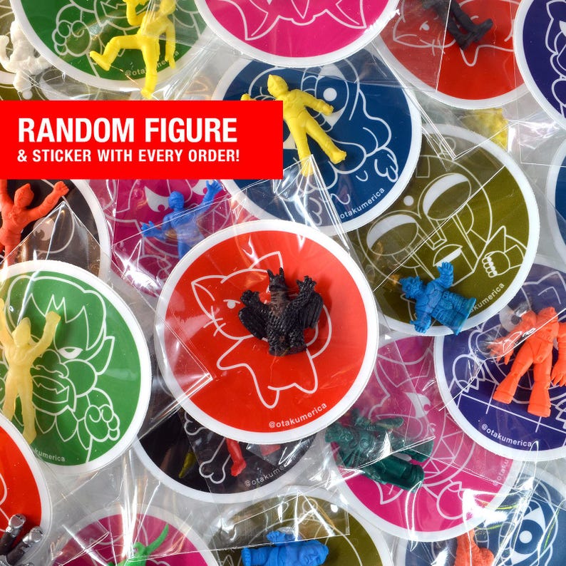 K&ouml;nnte beinhalten: Eine Sammlung bunter Aufkleber und kleiner Plastikfiguren. Die Aufkleber sind rund mit verschiedenen Cartoon-Designs und dem Text "@otakumerica". Der Text "RANDOM FIGURE & STICKER WITH EVERY ORDER!" wird auf einem roten Banner angezeigt.