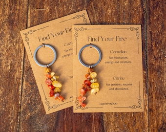 May include: Two keychains featuring silver-tone metal rings attached to clusters of tumbled carnelian and citrine gemstone chips. Each keychain is mounted on a rectangular kraft paper display card printed with the text Find Your Fire.