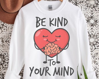 May include: White sweatshirt with a red heart holding a brain and the text "Be Kind to Your Mind".