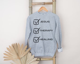 May include: A gray sweatshirt with a checklist graphic that says "Jesus", "Therapy", and "Healing" with checkmarks next to each item.
