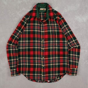 May include: A red, green, and yellow plaid flannel shirt with a green collar. The shirt has a button-down front and long sleeves. The collar has the text "ICEY" on a small tag.