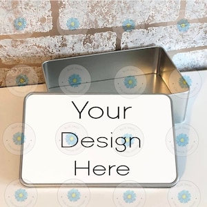 Puede incluir: Una lata rectangular plateada con una tapa blanca. La tapa tiene el texto "Your Design Here" impreso.