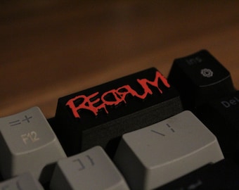 May include: A black keyboard with a red keycap that says "REDRUM" in a dripping font.