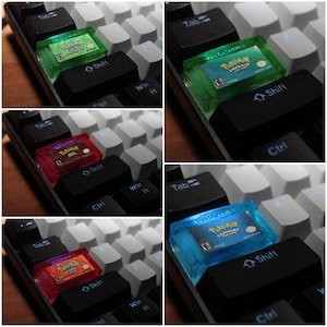 Könnte beinhalten: Eine Collage aus vier Bildern, die verschiedene farbige Spielpatronen für den Game Boy Advance zeigen. Die Patronen liegen auf einer schwarzen Tastatur mit weißen Tasten. Die Patronen sind für die Spiele Pokemon Emerald, Pokemon Ruby, Pokemon Sapphire und Pokemon Emerald.