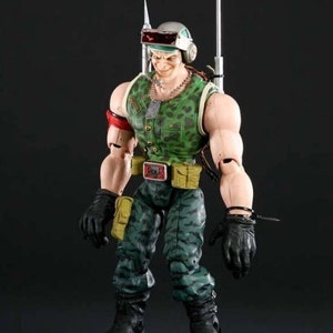 Könnte beinhalten: Eine Actionfigur in grün-schwarzer Tarnfarbe mit einem rot-silbernen Helm, einem silbernen Haken und einer silbernen Kettenkette. Die Figur trägt schwarze Handschuhe und schwarze Stiefel.