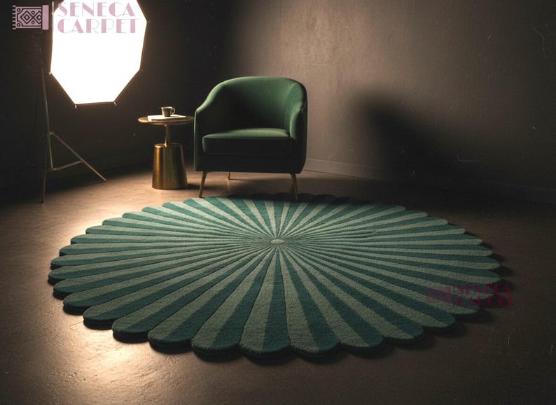 A wide shot shows a round, dark green and sage sunburst rug with a scalloped edge on the floor, accompanied by a green armchair and a studio lighting umbrella in the background.