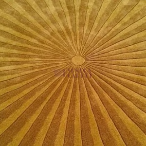 A close-up, overhead view of a mustard yellow round rug with a sunburst pattern radiating from the center.