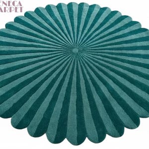 A round, scalloped tufted rug in dark teal with radial striped panels radiating from the center.