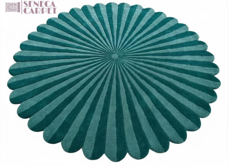 A round, scalloped tufted rug in dark teal with radial striped panels radiating from the center.