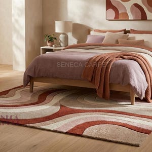 May include: A rectangular area rug featuring a layered, wavy pattern in shades of terracotta, cream, and beige. The rug has a textured, tufted surface with curved lines that create a rhythmic, flowing design across the entire floor covering.