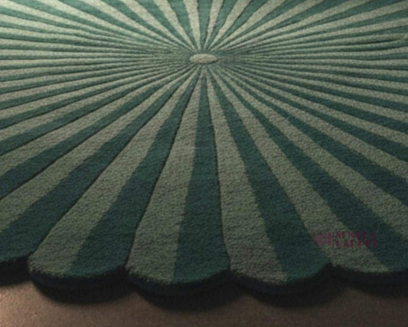 A close-up view of the textured surface of the round green rug, showing its scalloped edge and radial striped sunburst pattern meeting at a center circle.