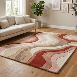 May include: A rectangular area rug featuring a layered, wavy pattern in shades of terracotta, dusty rose, cream, and beige. The design consists of smooth, flowing curves that span the entire surface, creating a textured, multi-dimensional appearance.