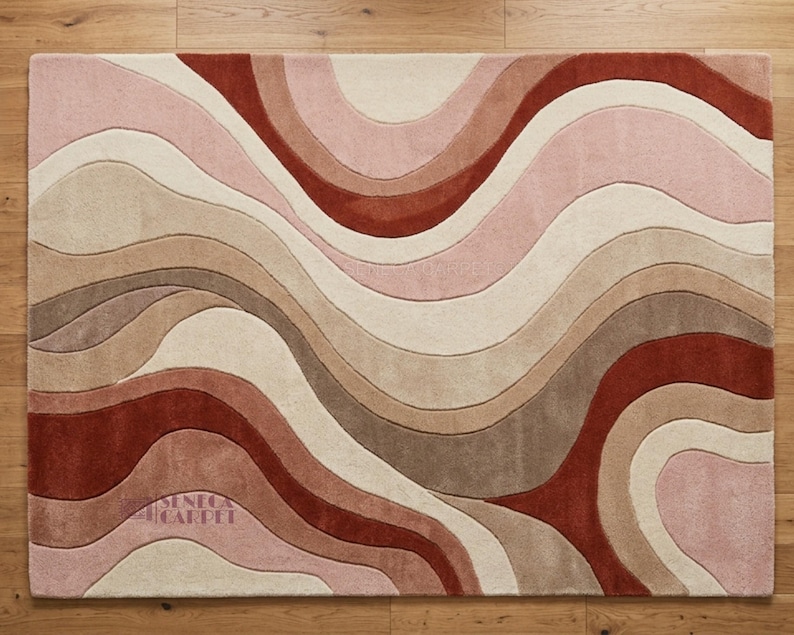 A top-down view of a rectangular rug with wavy abstract patterns in shades of pink, terracotta, and beige.