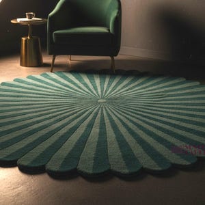 May include: A circular rug featuring a scalloped edge and a radial pattern of alternating dark teal and light teal stripes that converge at the center. The rug has a textured surface and a distinct flower-like shape with rounded petal segments.