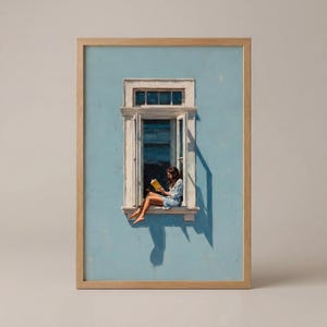 Può includere: Una stampa artistica incorniciata raffigura una persona che legge un libro in una finestra. La finestra è bianca, su un muro azzurro. La persona indossa un vestito blu e tiene in mano un libro giallo. La cornice è marrone chiaro.