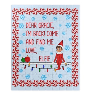 May include: A jigsaw puzzle with a light blue background featuring red and white peppermint candy borders and blue snowflakes. The text reads: DEAR GRACIE, I'M BACK! COME AND FIND ME. LOVE, ELFIE. An elf sits on a shelf with Christmas lights.