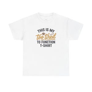 Puede incluir: Camiseta blanca con el texto "THIS IS MY too tired TO FUNCTION T-SHIRT" en negro, marrón y dorado. El diseño incluye una taza de café y ZZZ, lo que sugiere fatiga. Una camiseta casual y cómoda.