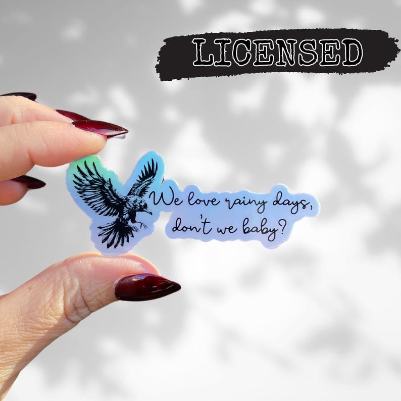 May include: A holographic sticker with a black and white illustration of a bird flying with the text "We love rainy days, don't we baby?"