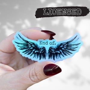 May include: A blue and white iridescent sticker with a pair of black angel wings and the text "End of."