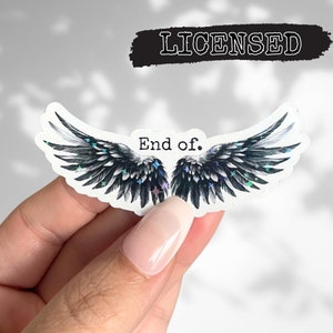 May include: A sticker with a pair of black angel wings with iridescent glitter. The wings are spread open and the text "End of." is printed in black in the center of the wings.