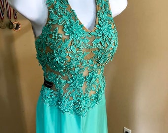 May include: A turquoise halter-style dress with a sheer bodice featuring intricate floral embroidery. The dress has a fitted bodice and a flowing skirt.